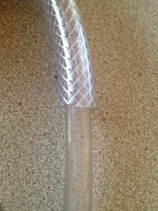 Remove the white coupler fitting - it is not glued on and insert the pvc tube inside the reinforced tube until the fit is secure.
